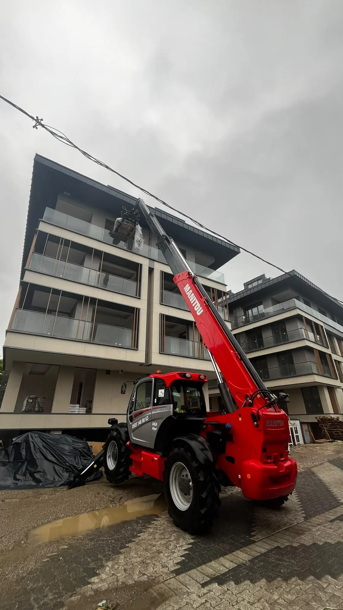Manitou teleskopik yükleyici ile binanın çatı katına malzeme çıkarma